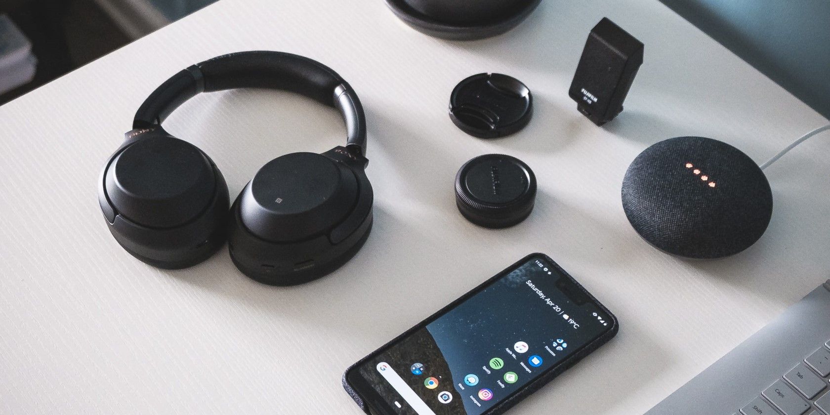 black google nest mini on a table with a phone and headphone