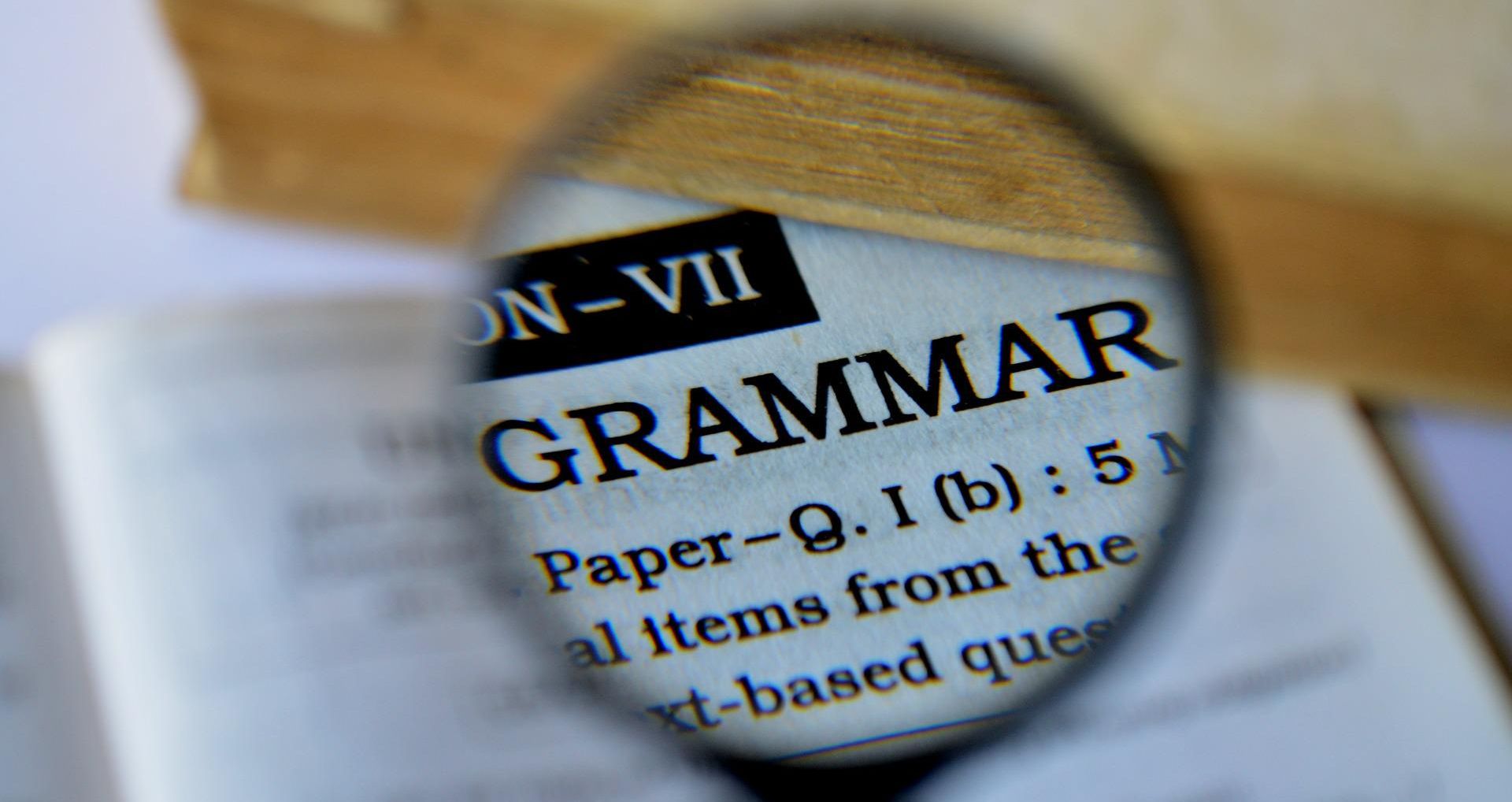 magnifying glass showing word "grammar" on paper