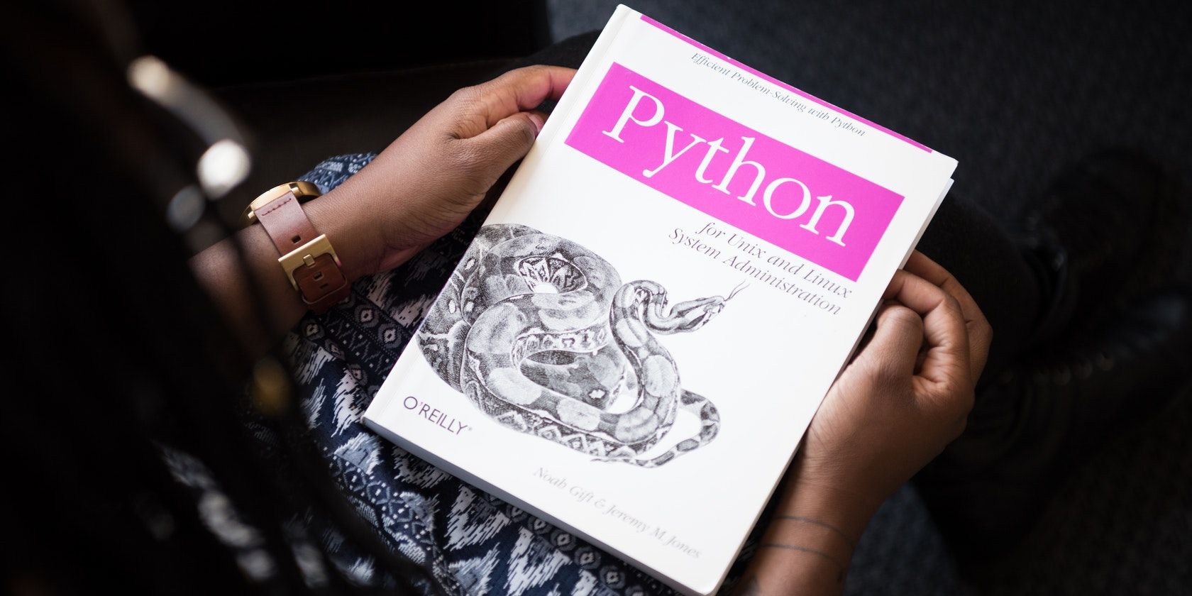 An O'Reilly Python book, featuring a large snake on the cover, held in somebody's hands 