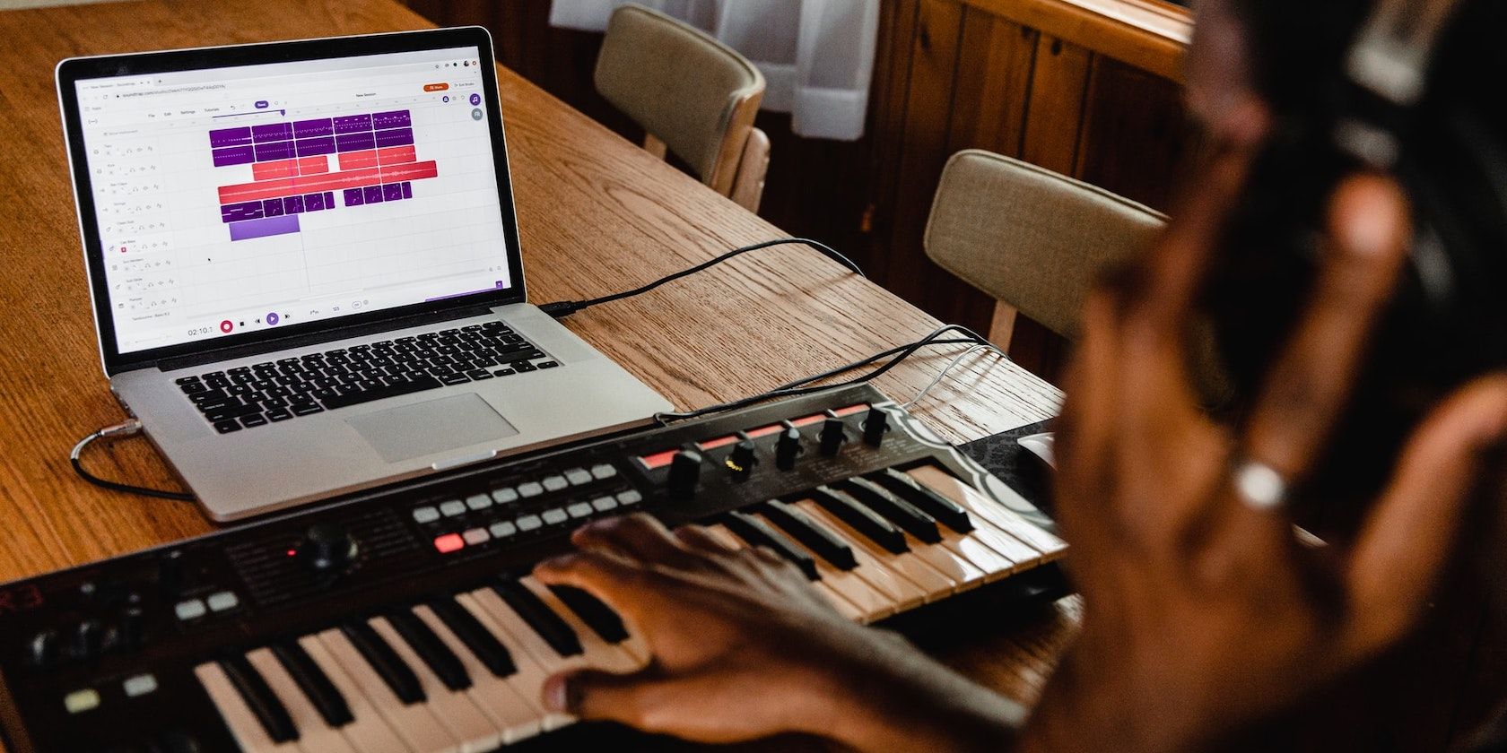 A person playing a MIDI keyboard and recording using a browser-based DAW.