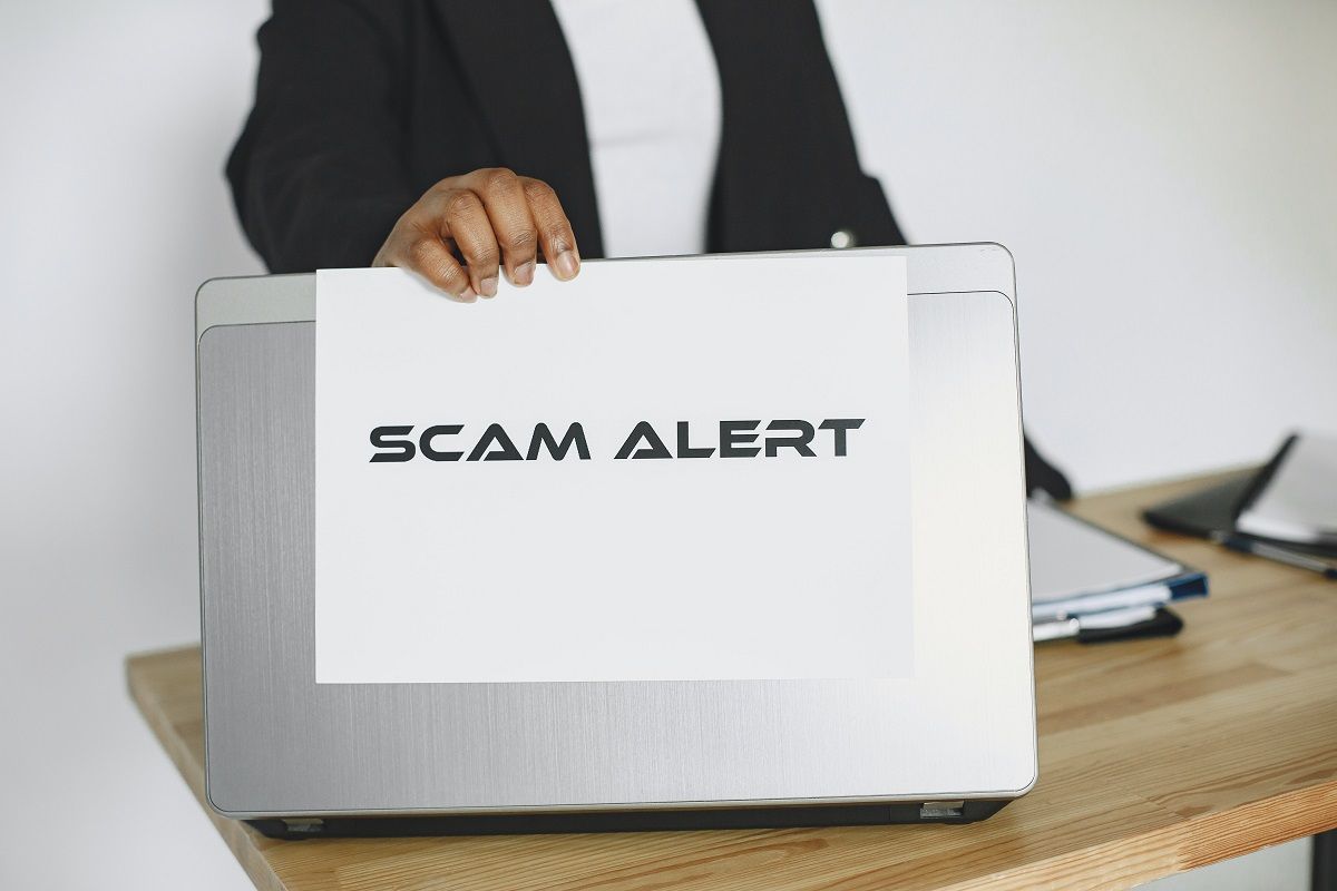 man holding sheet of paper written scam alert