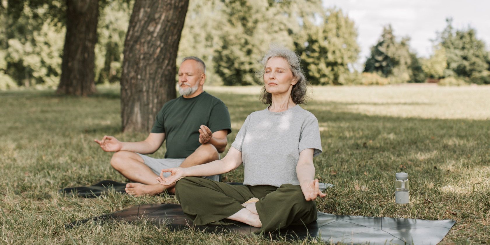 Senior couple sitting outside exercising and meditating