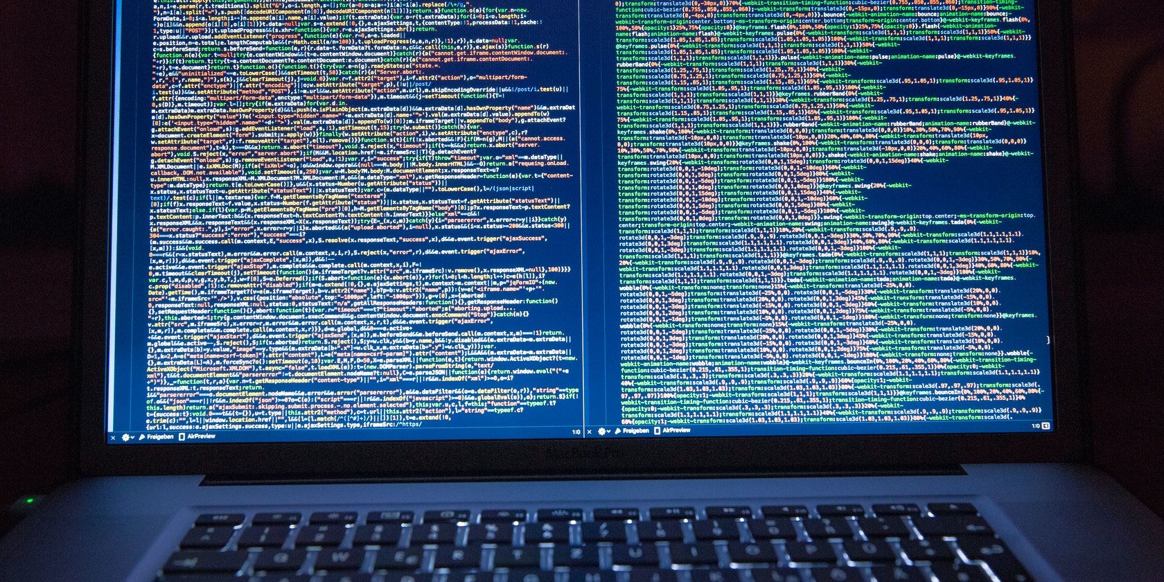 A close-up of a laptop screen showing lines of source code in two windows side-by-side