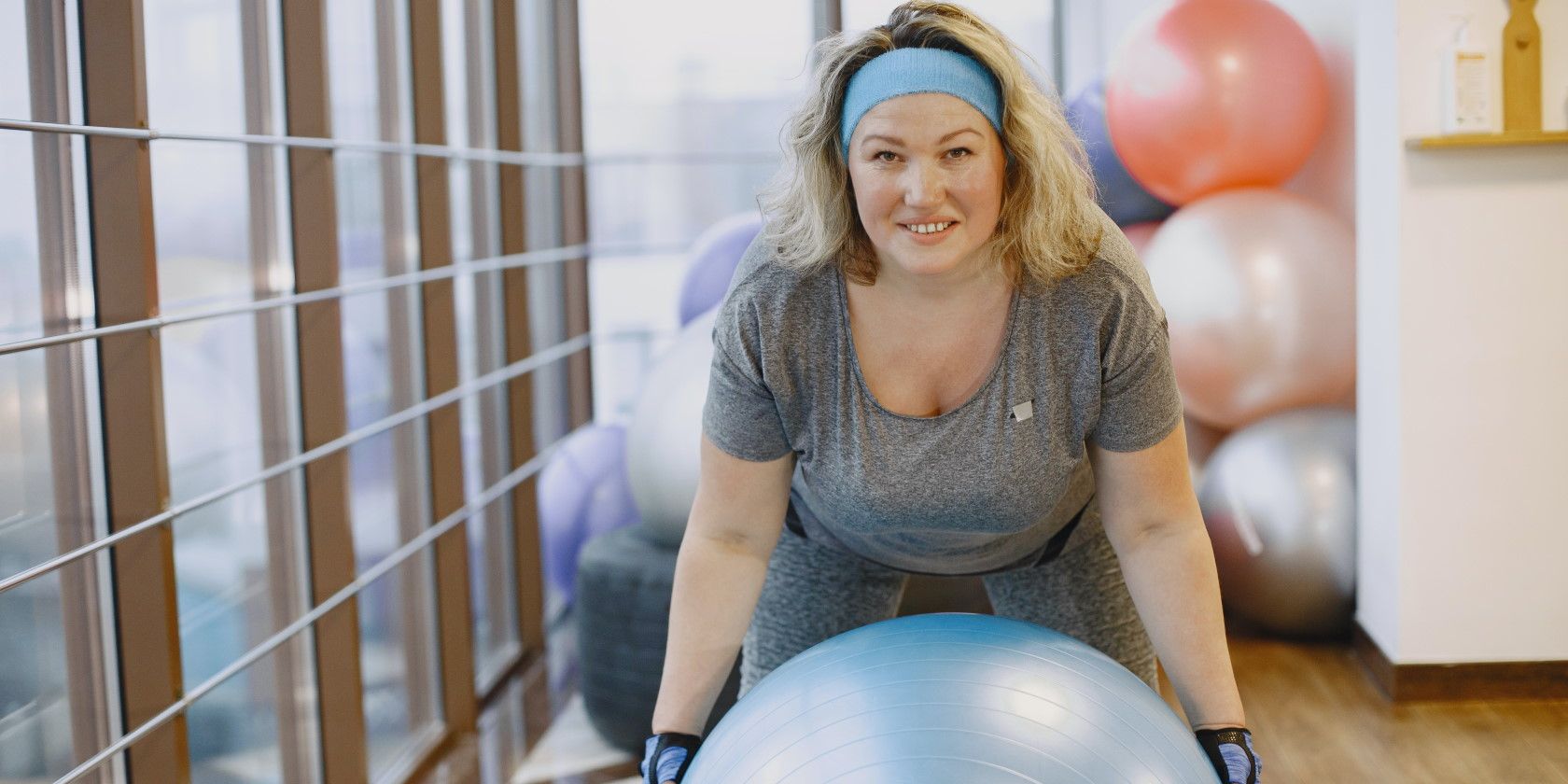 Smiling woman wearing workout clothes and holding exercise ball