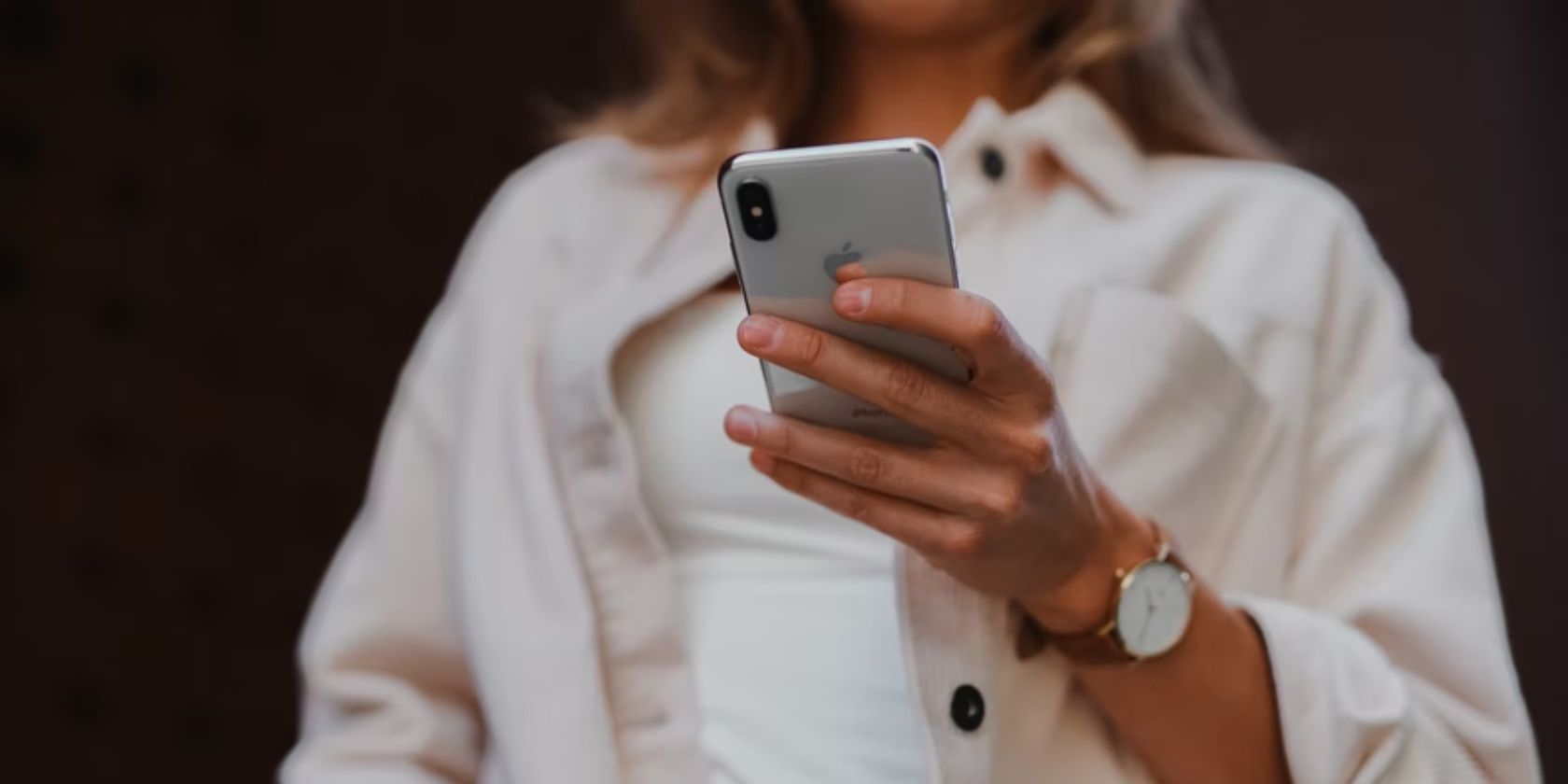 woman wearing white jacket holding an iphone