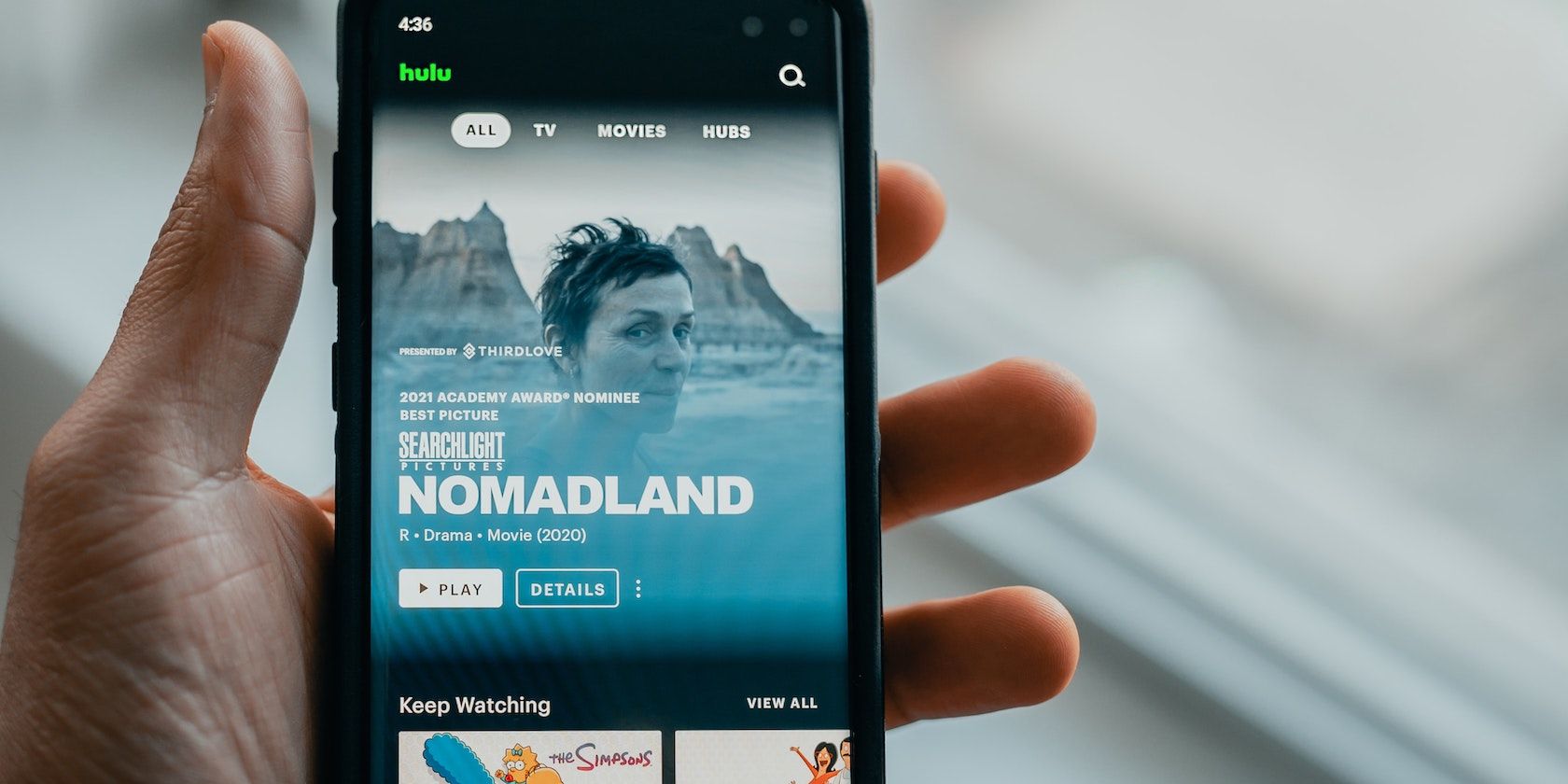 Person holding a phone with Hulu featured