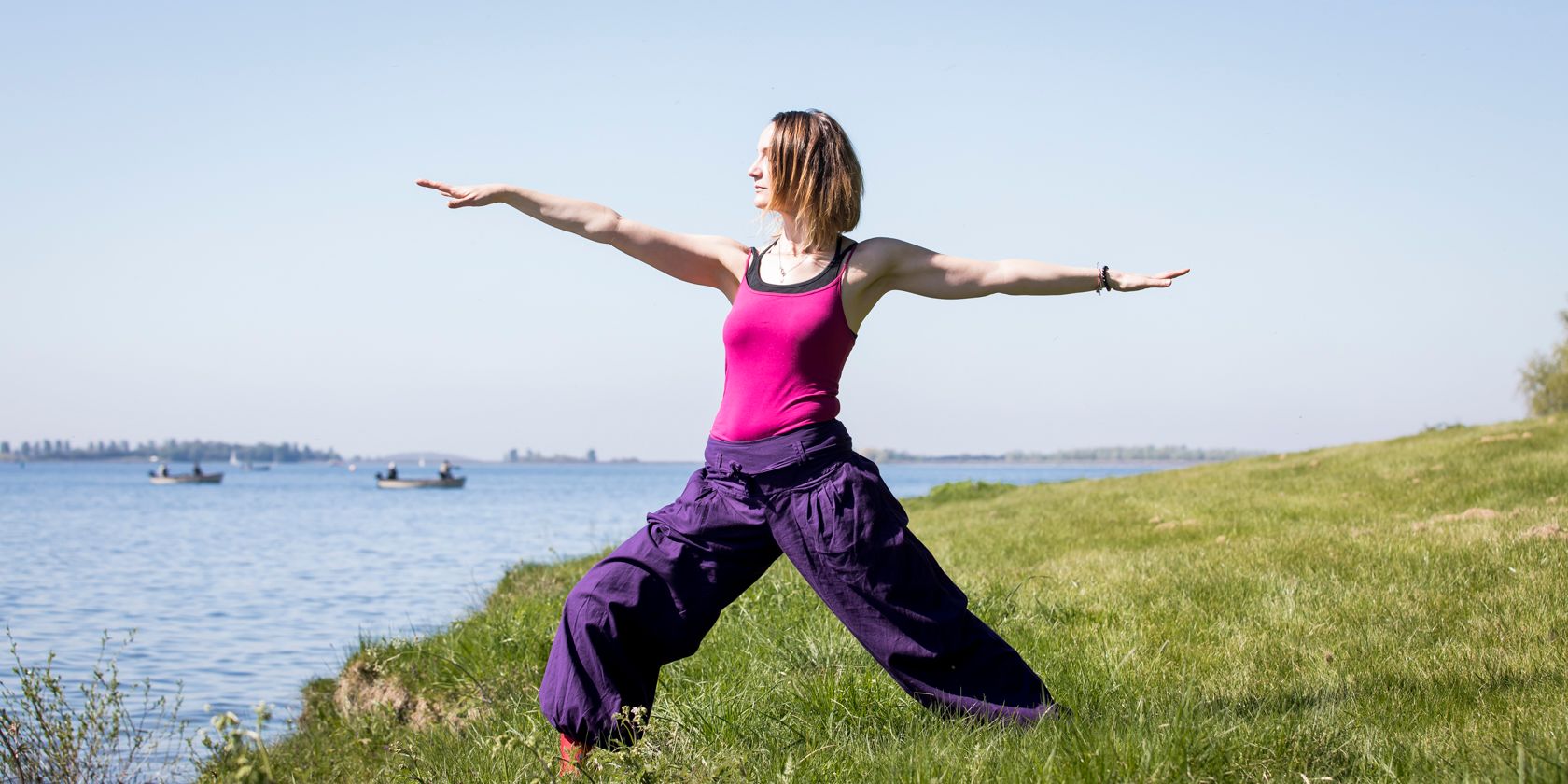 Woman doing yoga pose by a lakeside