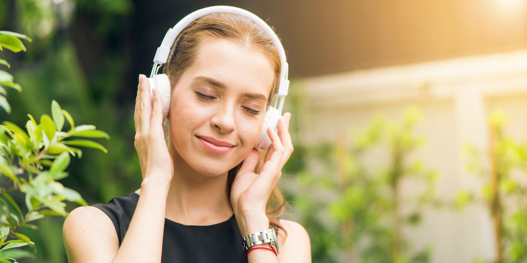 Woman in a black vest listening to headphones and smiling