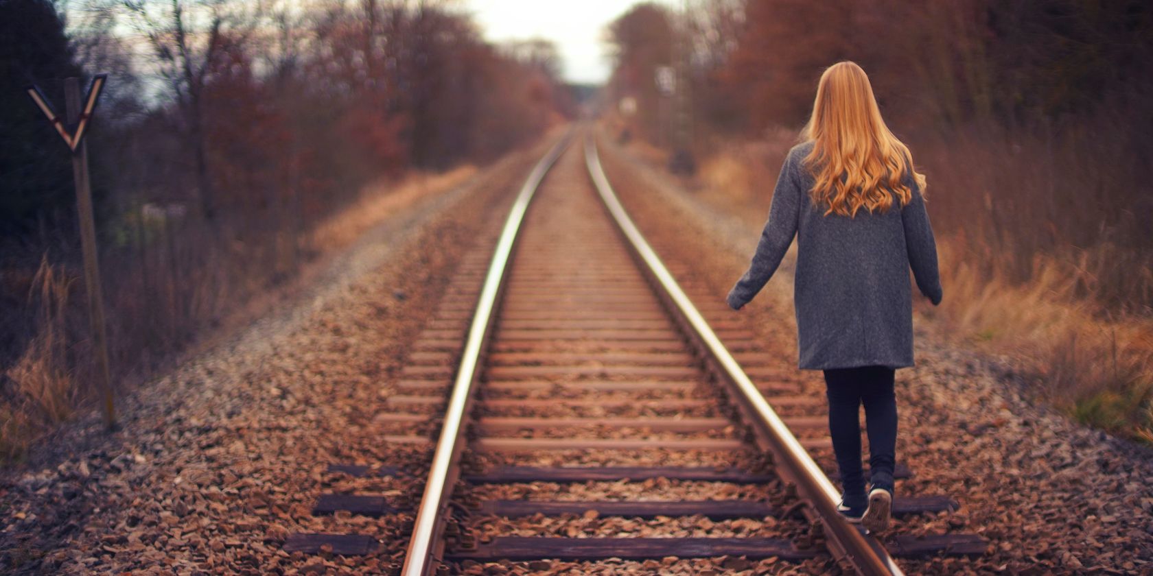 Woman walking away down the side of a train track