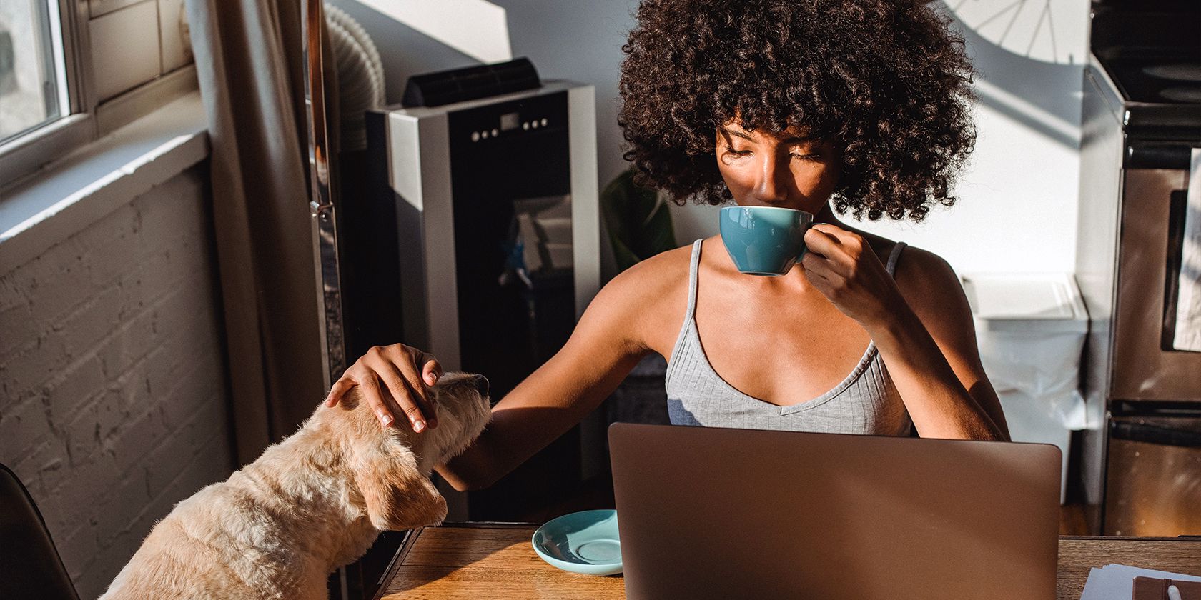 an online freelancer petting her dog and drinking coffee while working