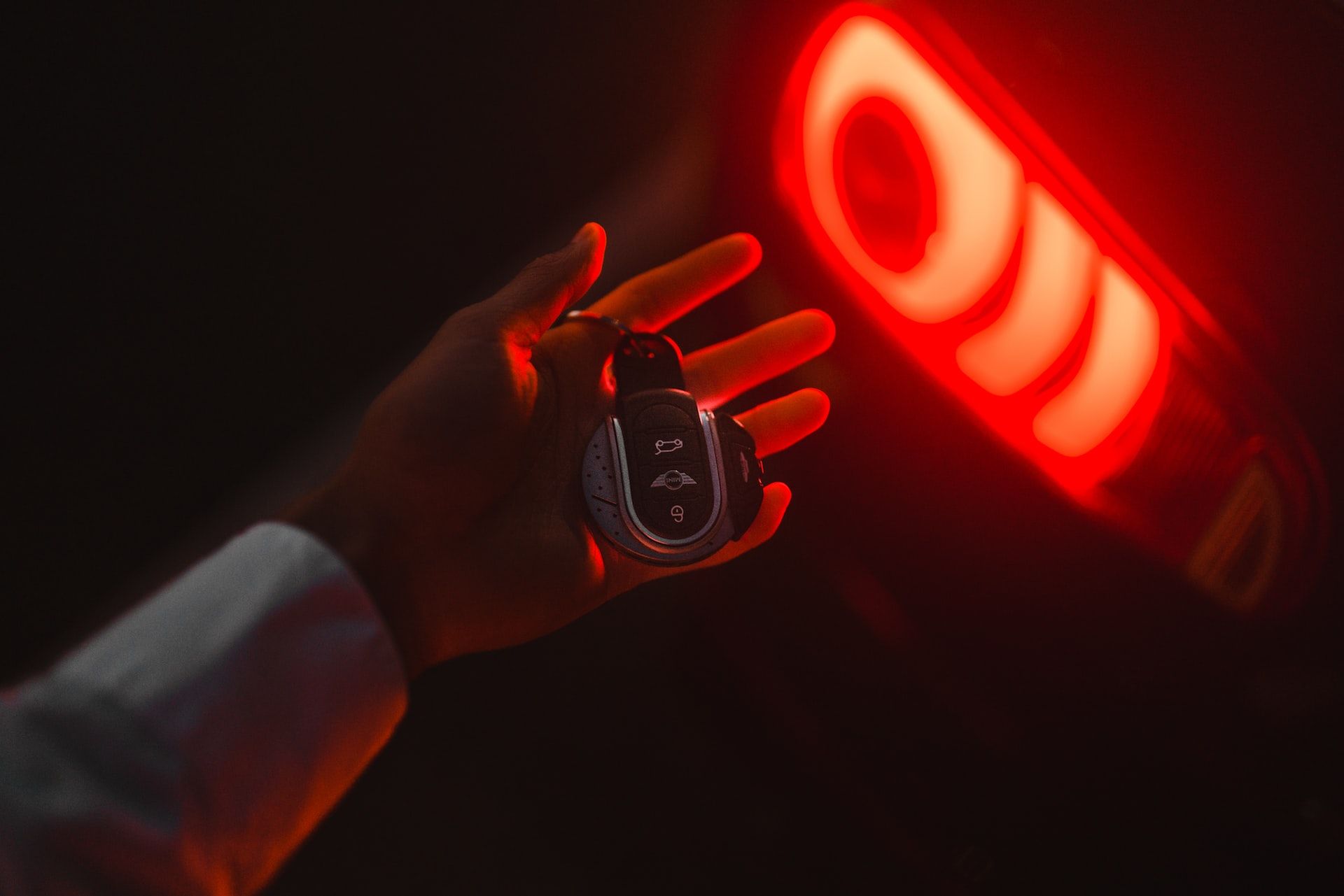 Person holding a car smart key against a red light