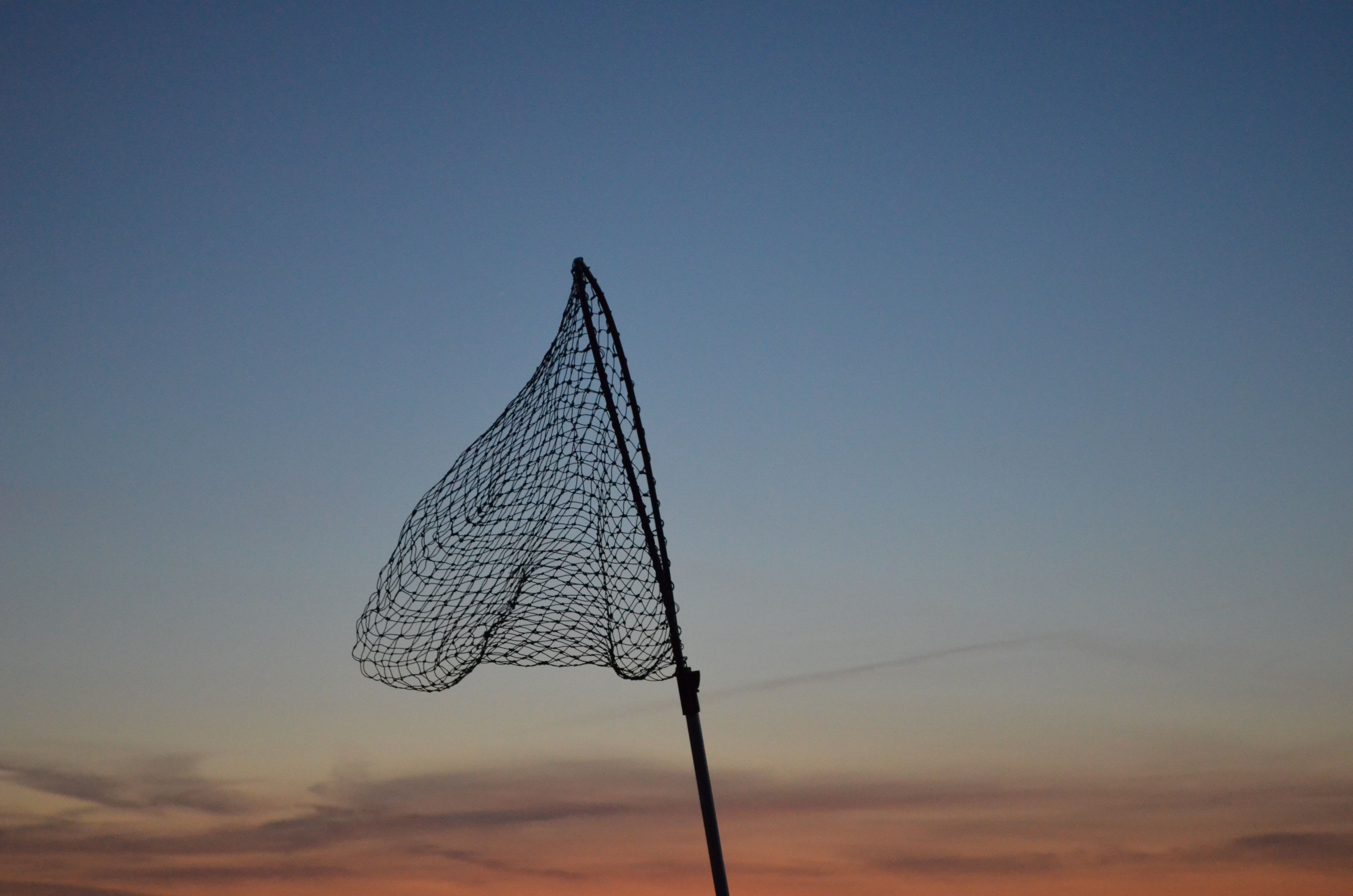 a fishing net held aloft against the sunset