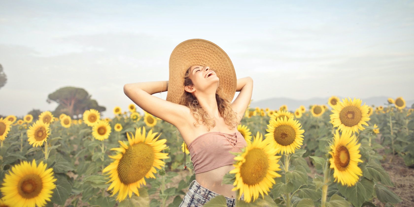happy woman standing smiling in sunflower field