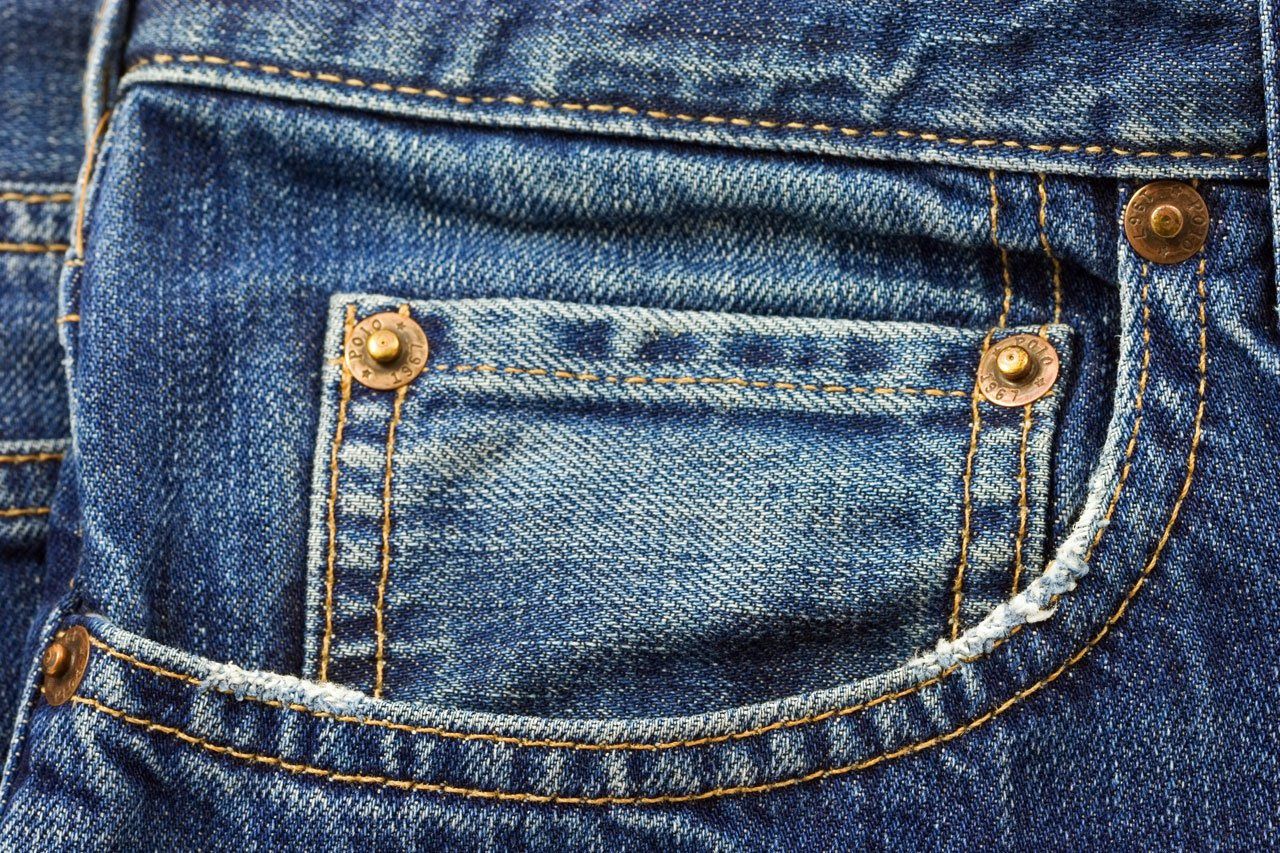A close-up of a jean pocket with copper rivets