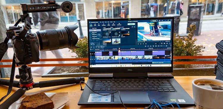 laptop with video editing software running with video camera on tripod beside it