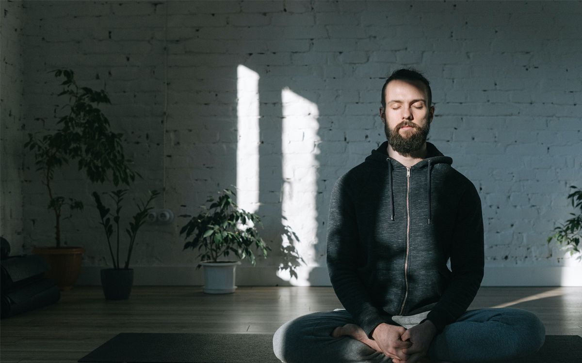 Um homem meditando em um tapete de ioga