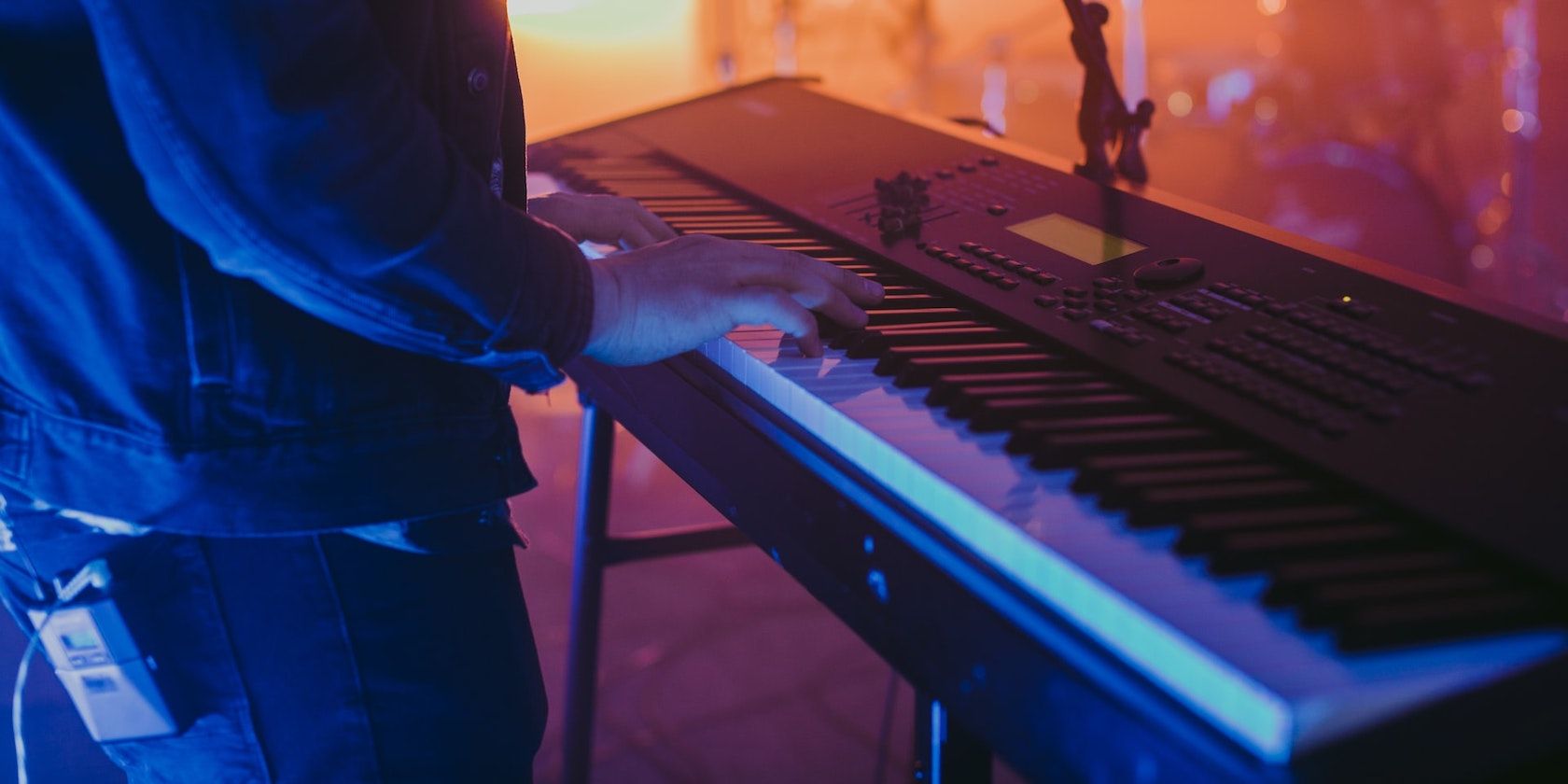 A person playing a MIDI keyboard at a live music performance.