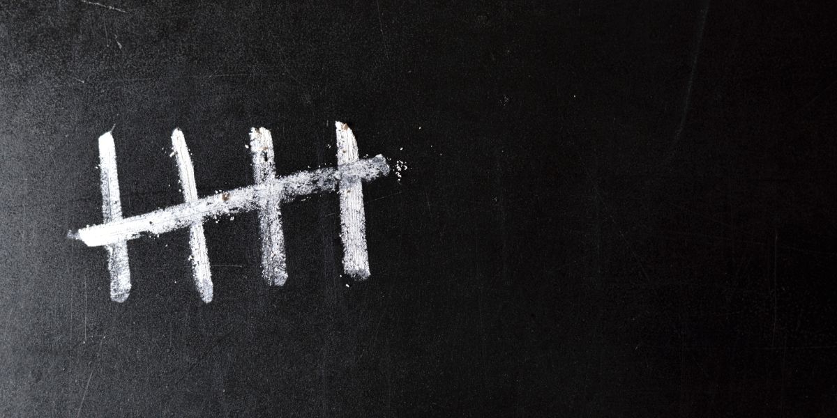 picture of the number five in a tally written with chalk on a black background