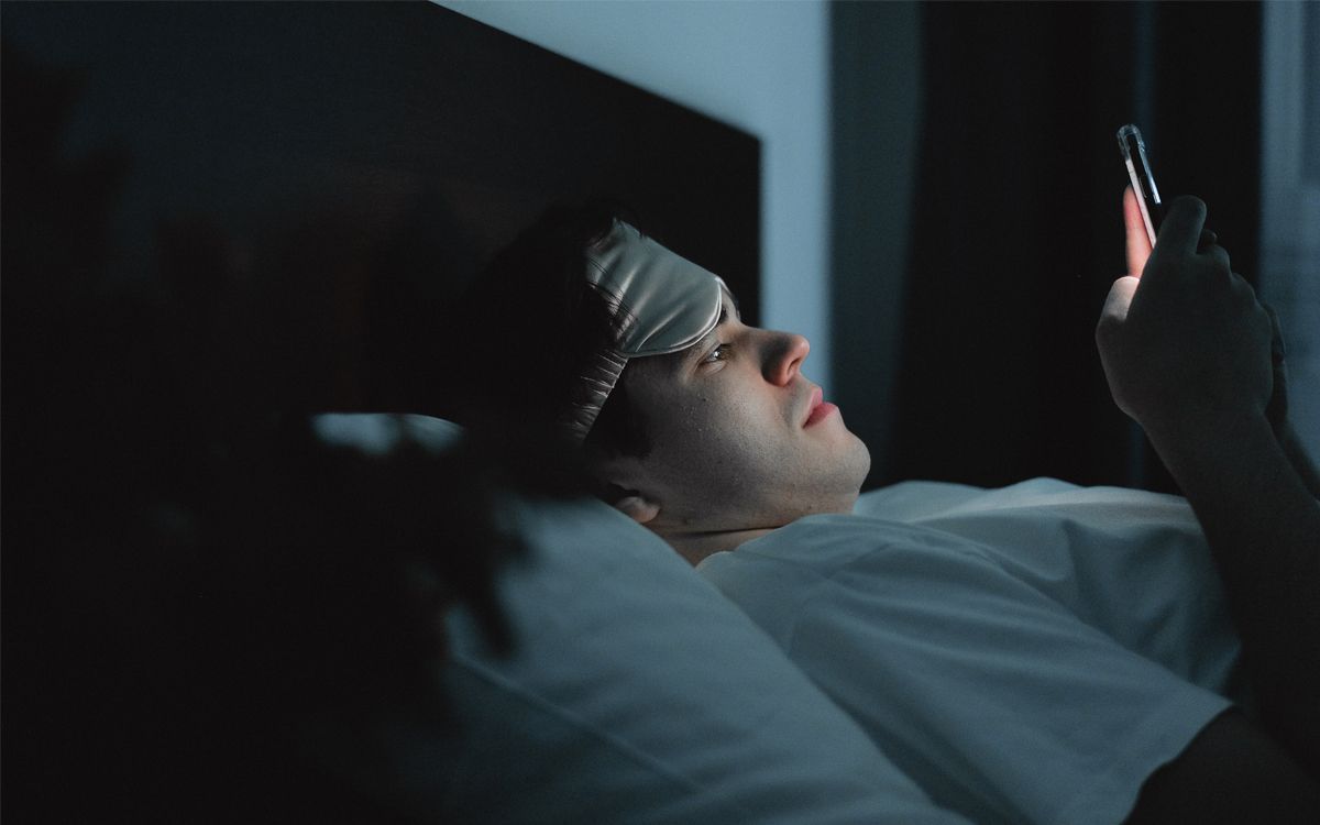 A man using his phone in the dark while in bed