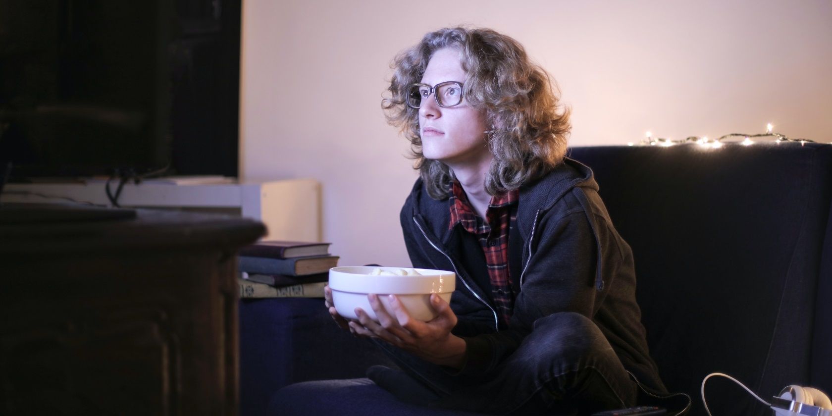 woman watches tv at home holding bowl of popcorn
