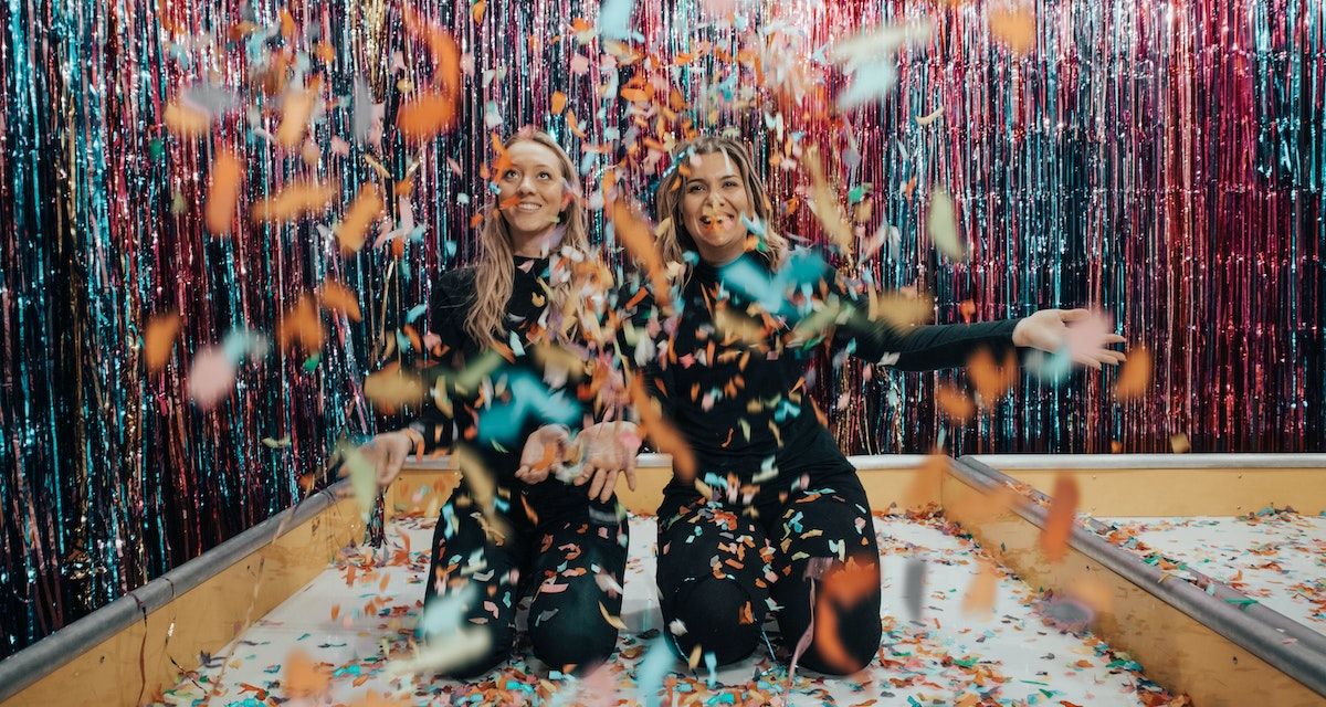 two woman throwing confetti
