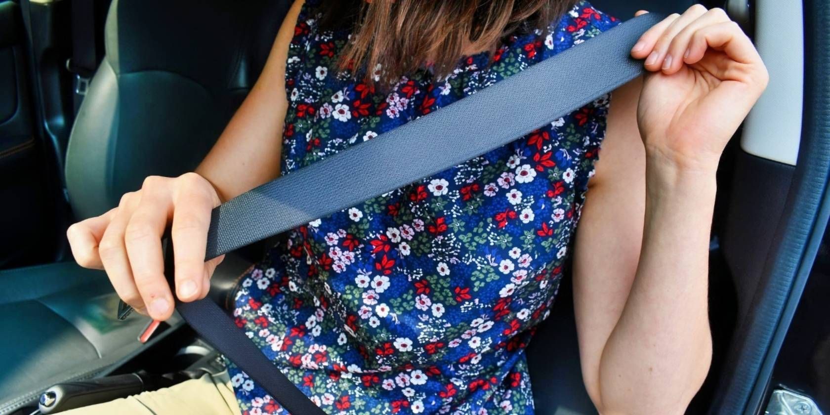 A woman putting on a seat belt in a vehicle