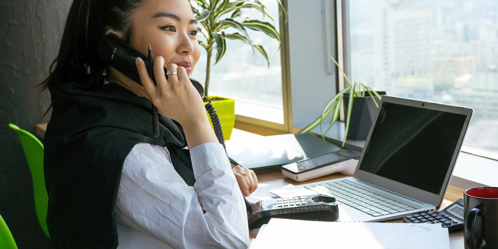 A Woman at Workstation While Having a Telephone Call