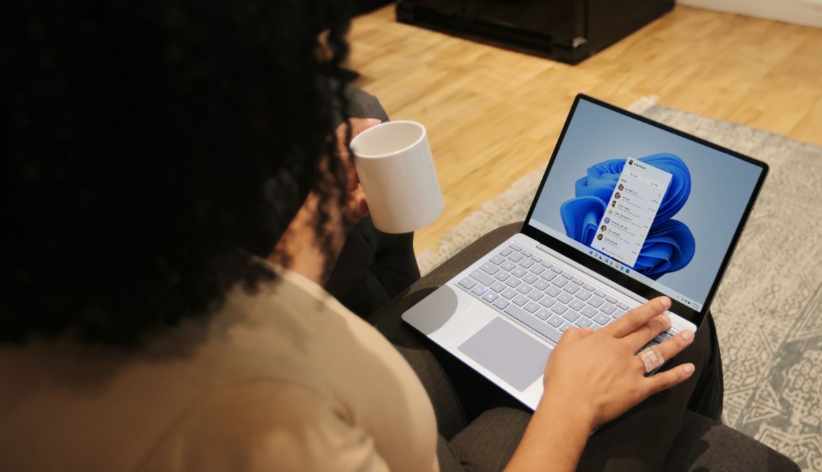Une femme qui utilise un PC Windows en tenant une tasse.