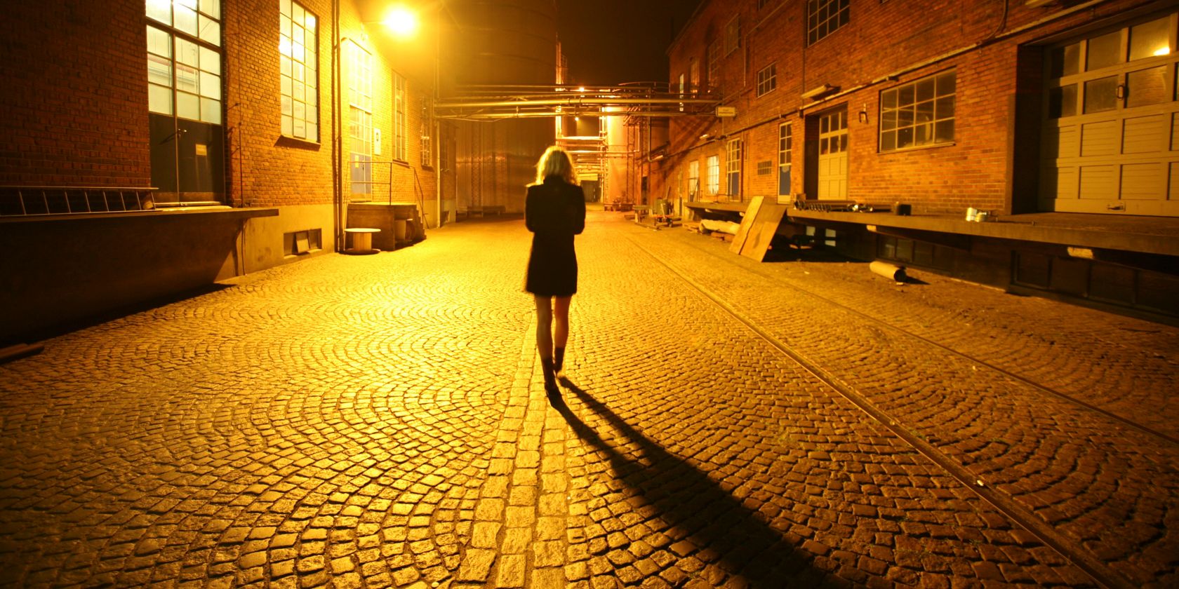 A woman walks alone down a city street at night