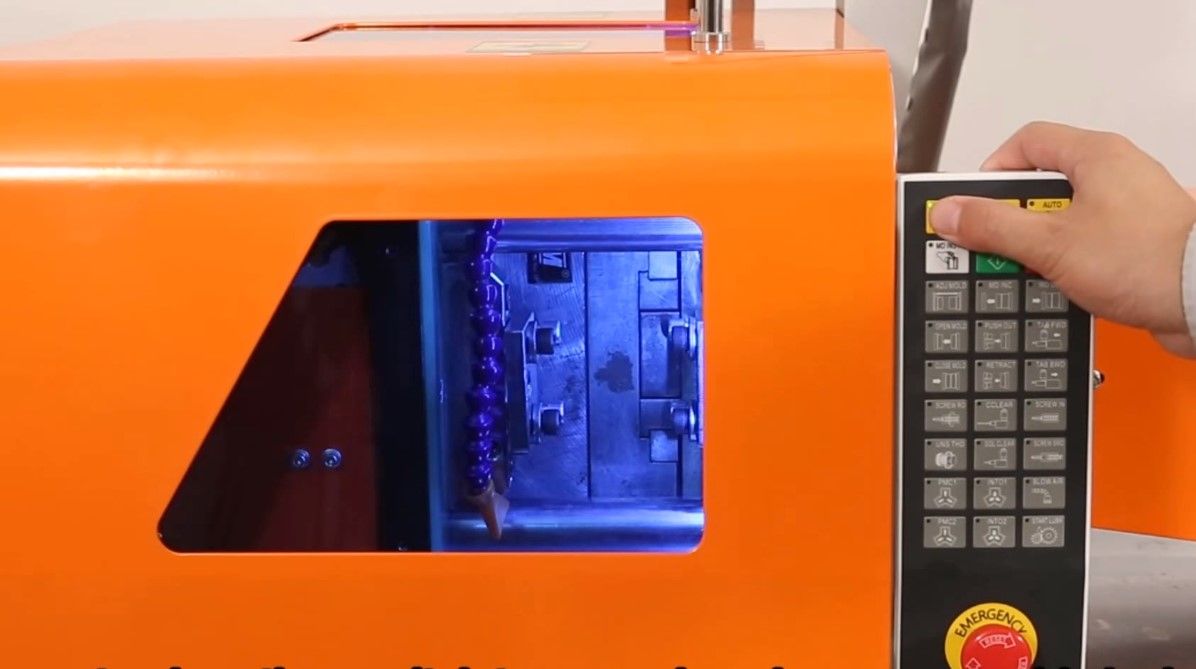 A hand setting up an electric injection molding machine