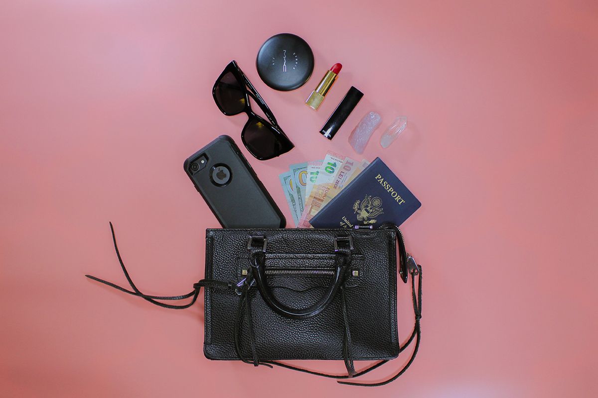 Black handbag with phone, passport, europes, makeup coming out the top.