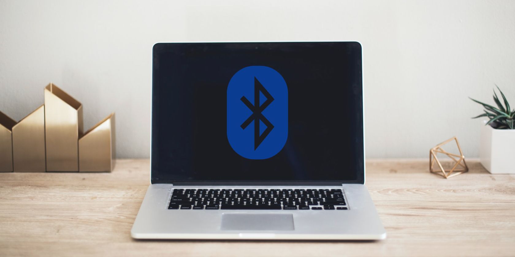 A laptop on a wooden table with a Bluetooth logo on it