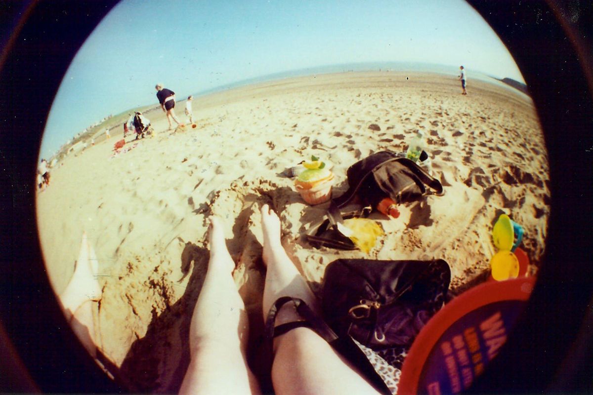 Fisheye photo of woman's legs on sand.