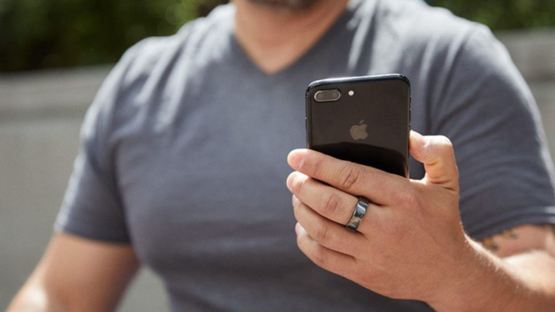 Man outside wearing Oura Ring 3 and holding an iphone