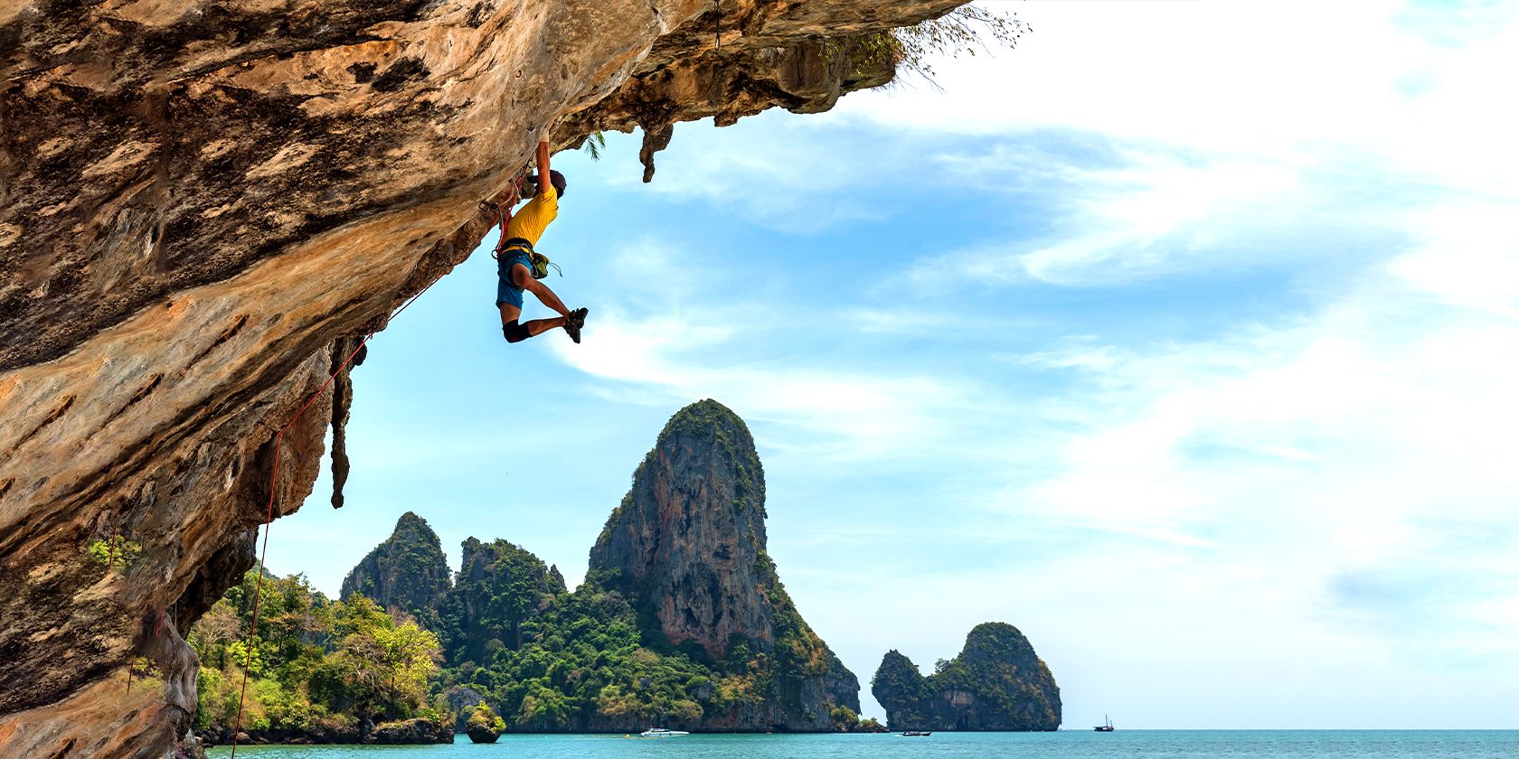 Mountain climber going up a cliff over the sea