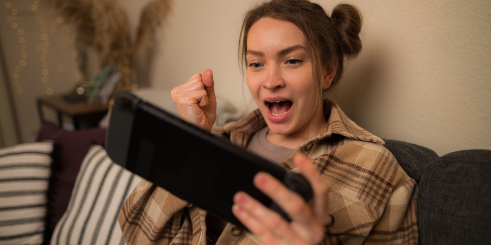 Excited girl holding up fist while playing on Nintendo Switch in handheld mode