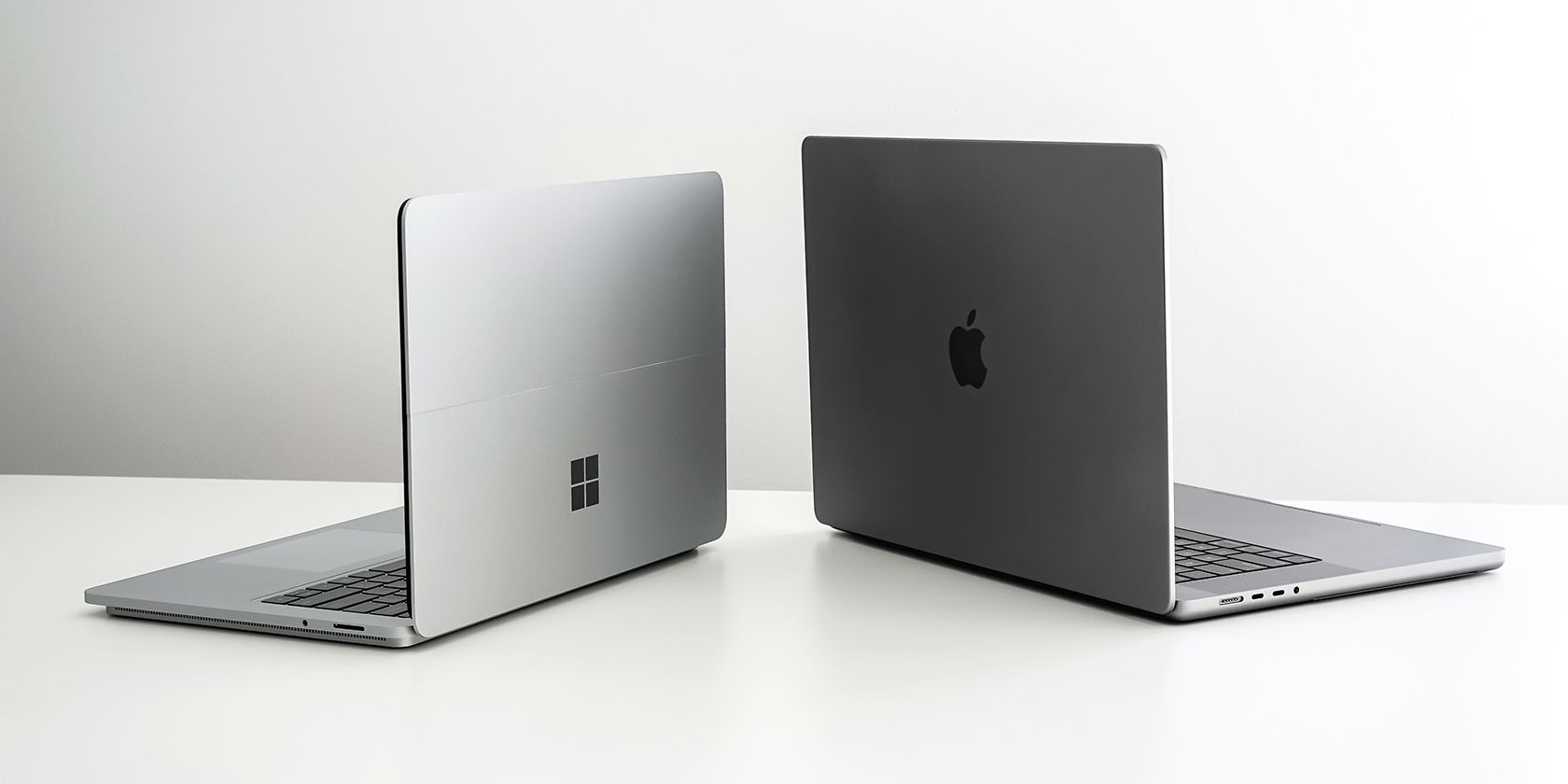 A Mac and a Windows Laptop Placed Side-by-Side on a White Surface