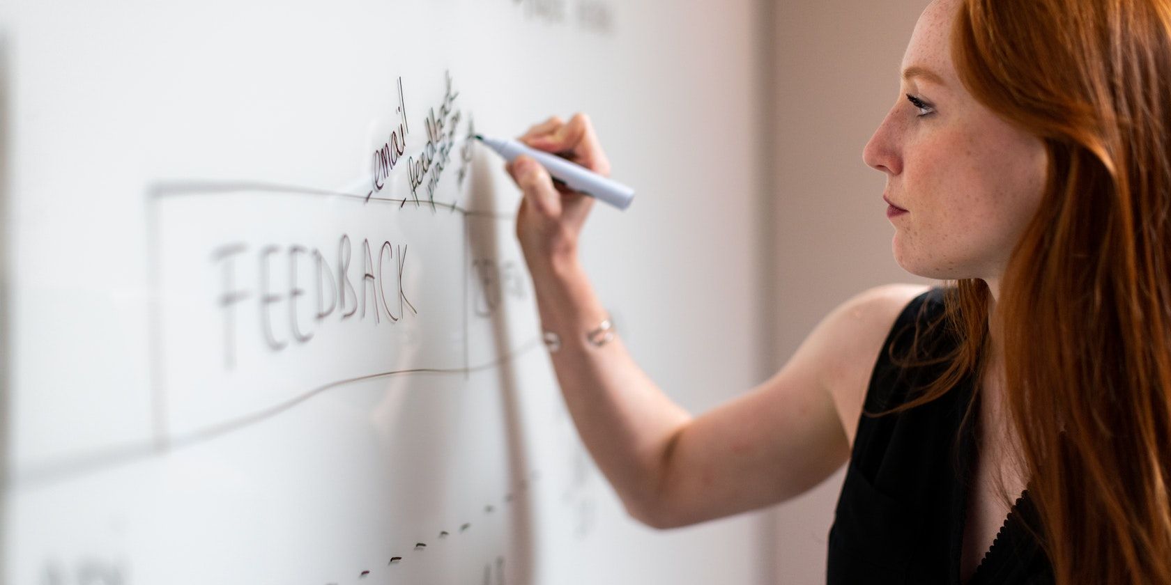 White Woman in black writing on a Whiteboard