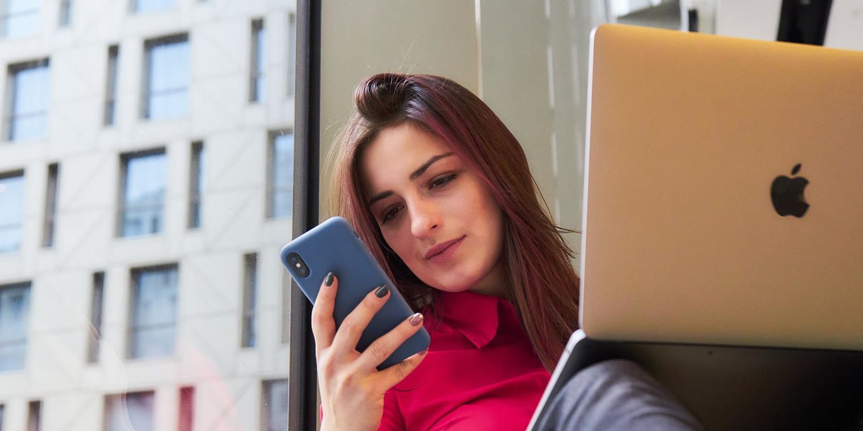 Woman looking at her mobile phone with laptop open