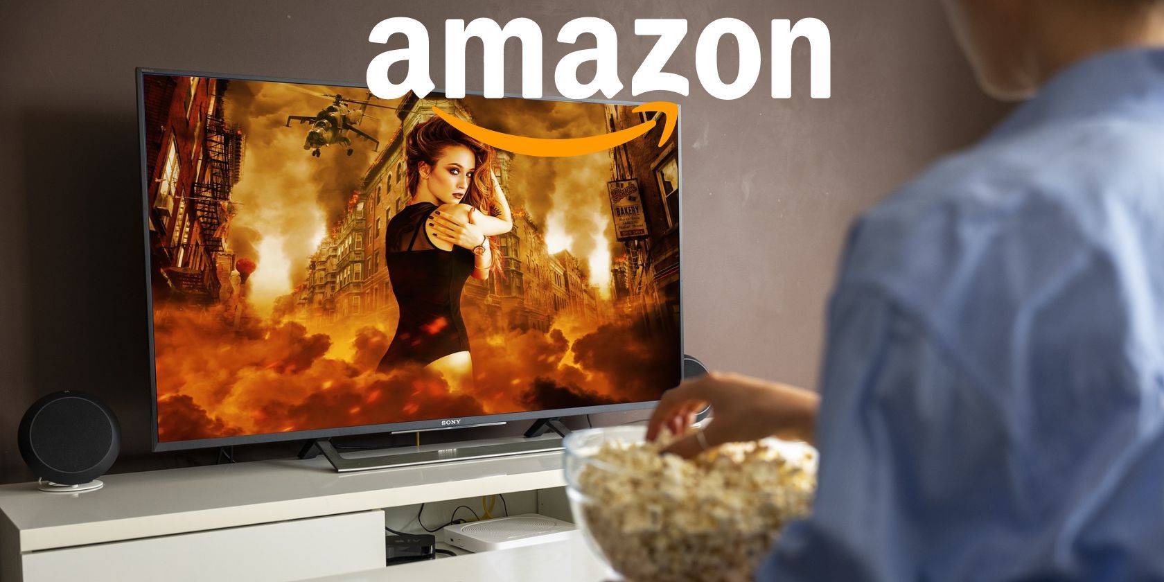A man with popcorn watching the TV with the Amazon logo superimposed