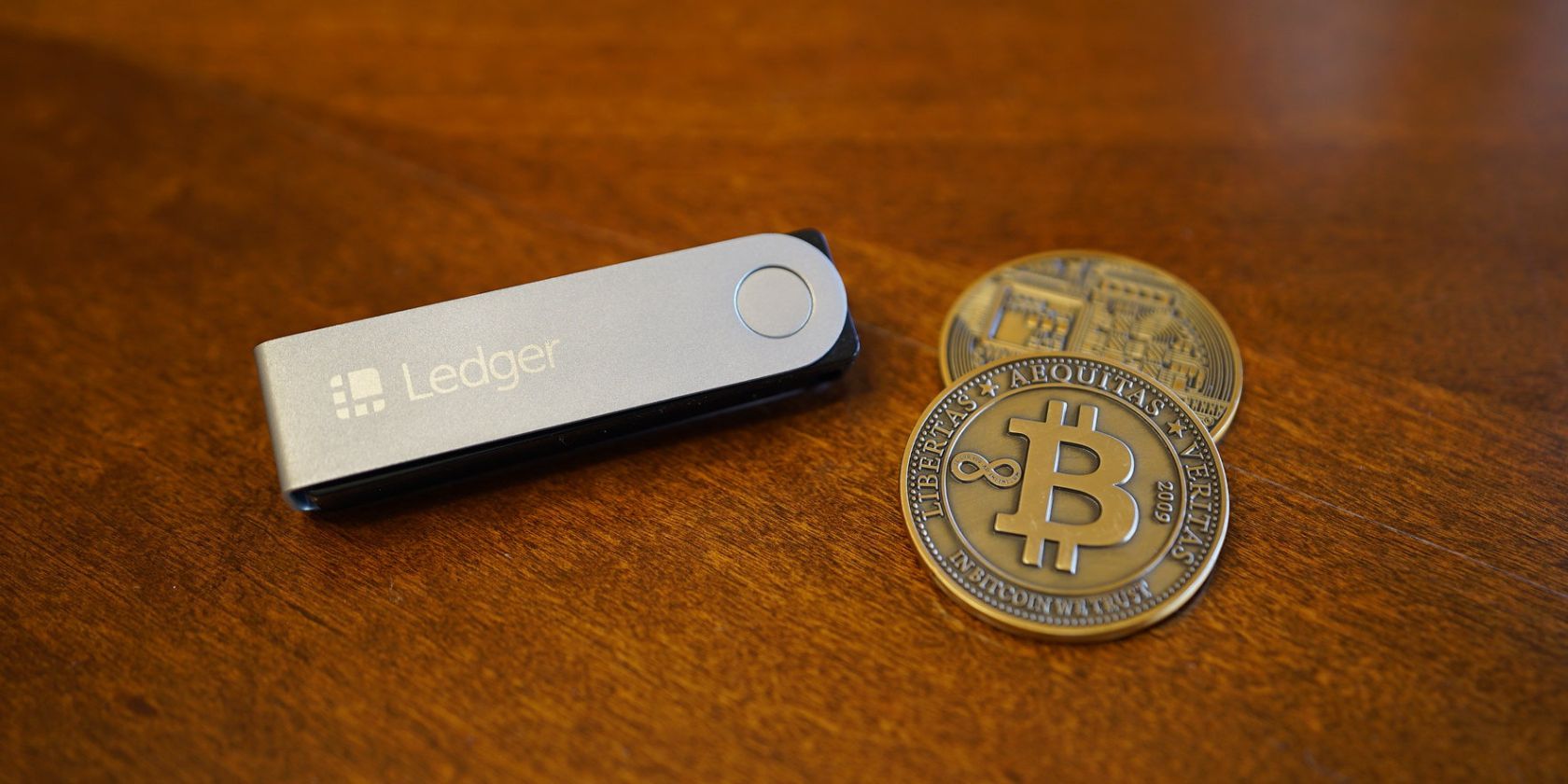 bitcoins next to ledger hardware wallet on table