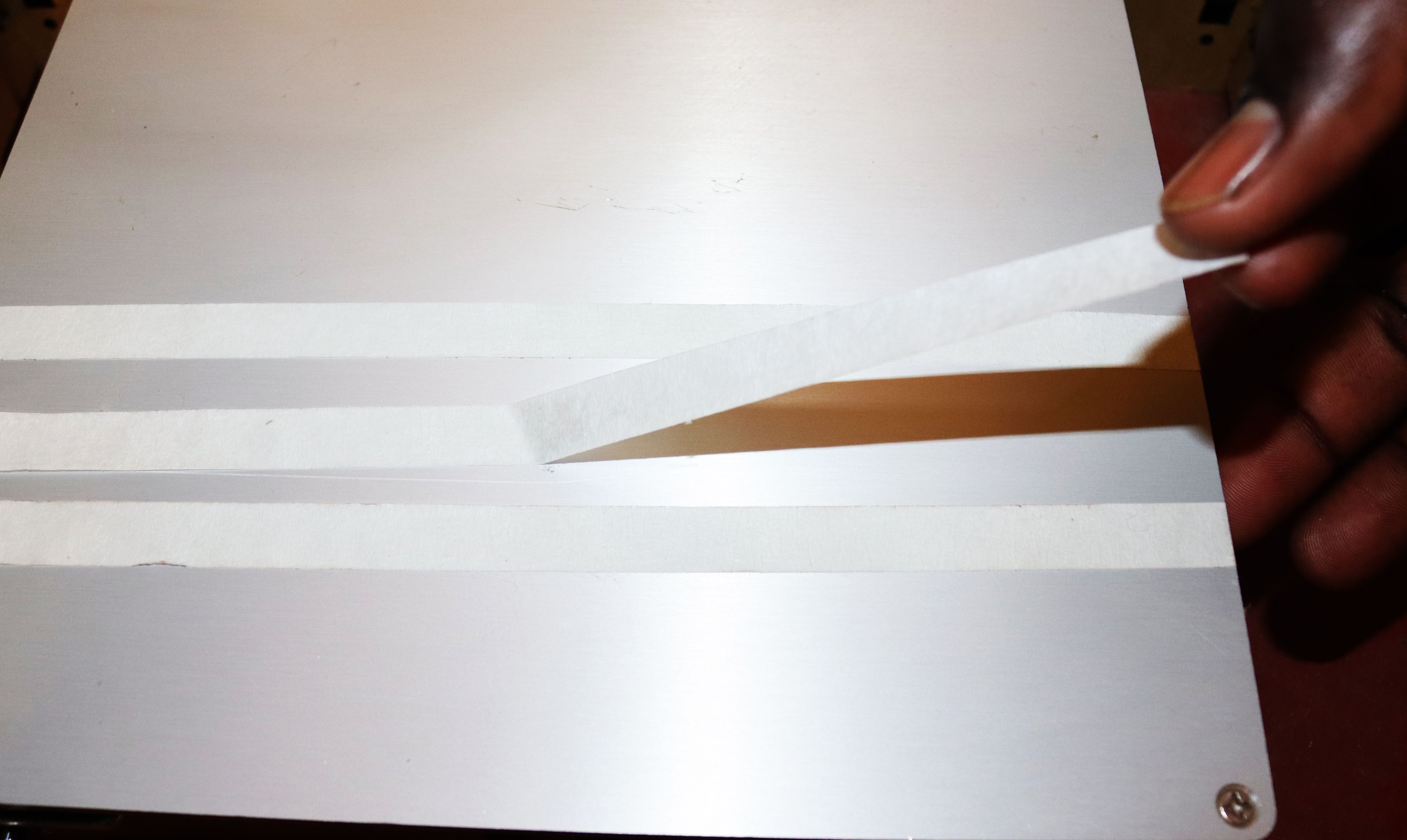 Using a masking tape to clean a 3D printer bed