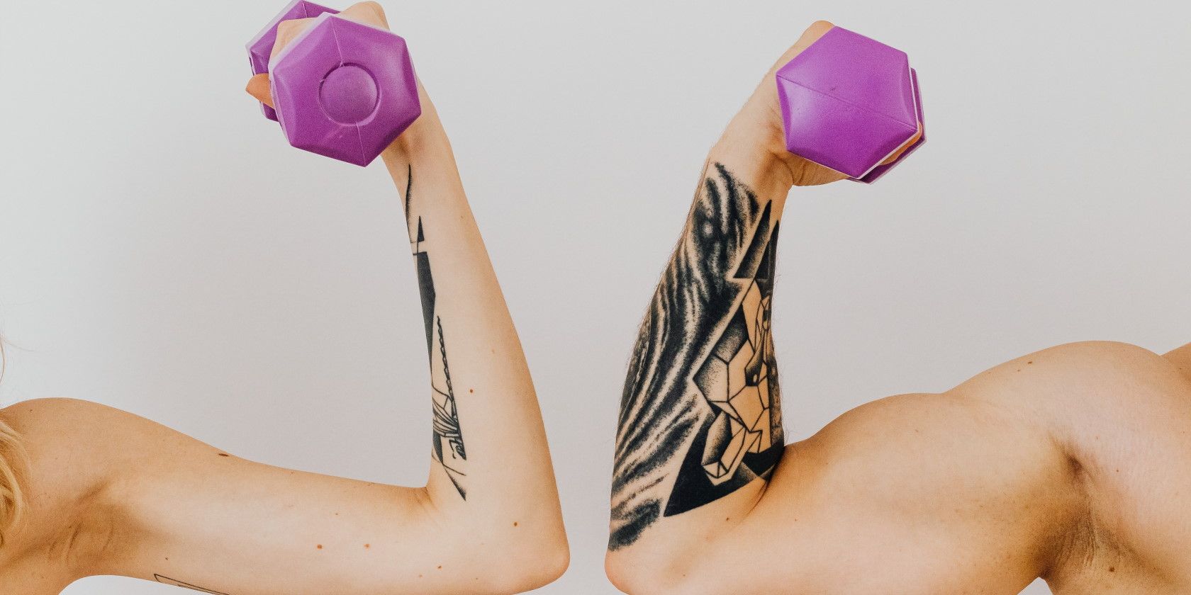 tattooed couple flexing arm muscles and holding purple dumbbells