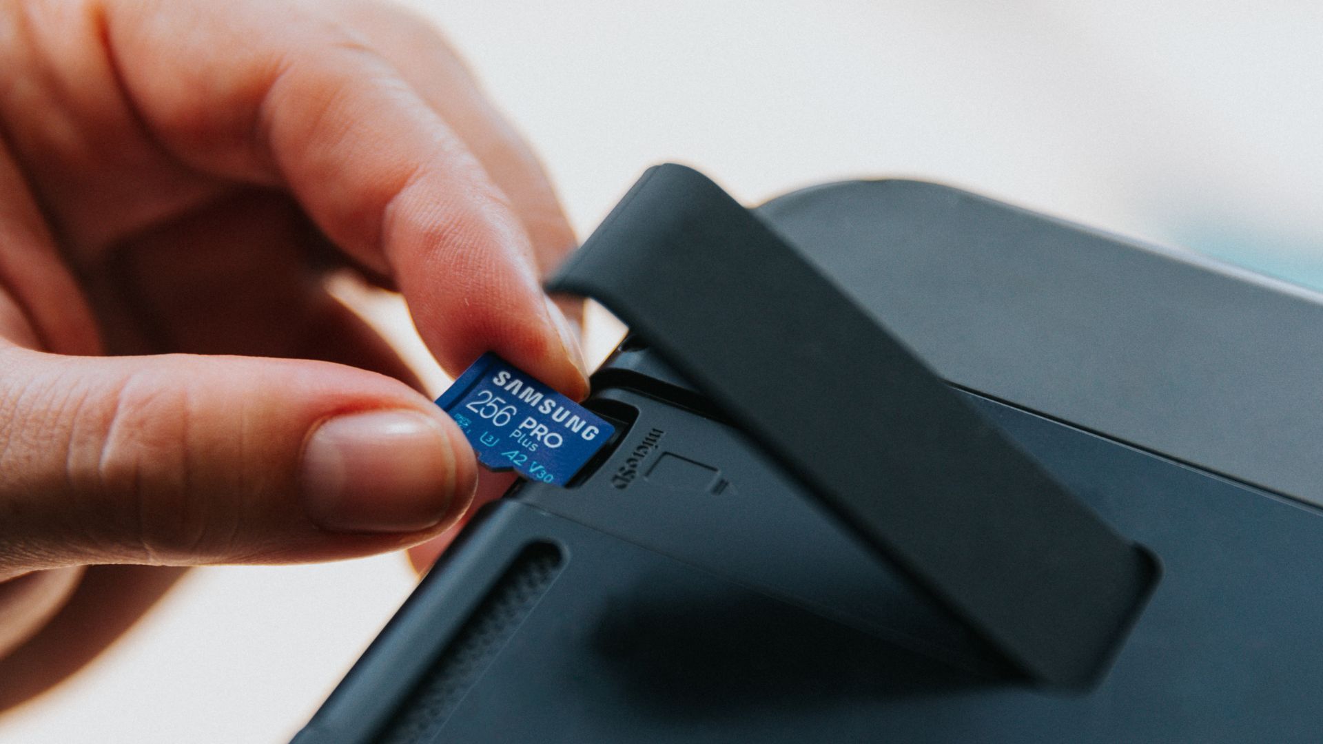 hand inserting a Samsung Pro Plus SD card into a Nintendo Switch