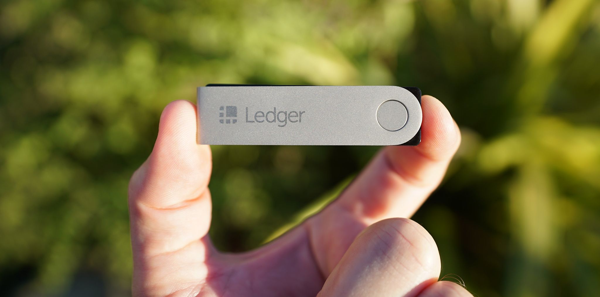 person holding ledger crypto wallet outside