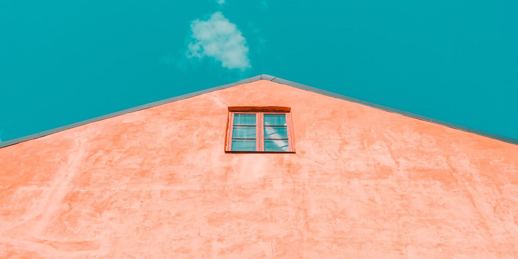 A low angle photo of a pink building against a blue sky