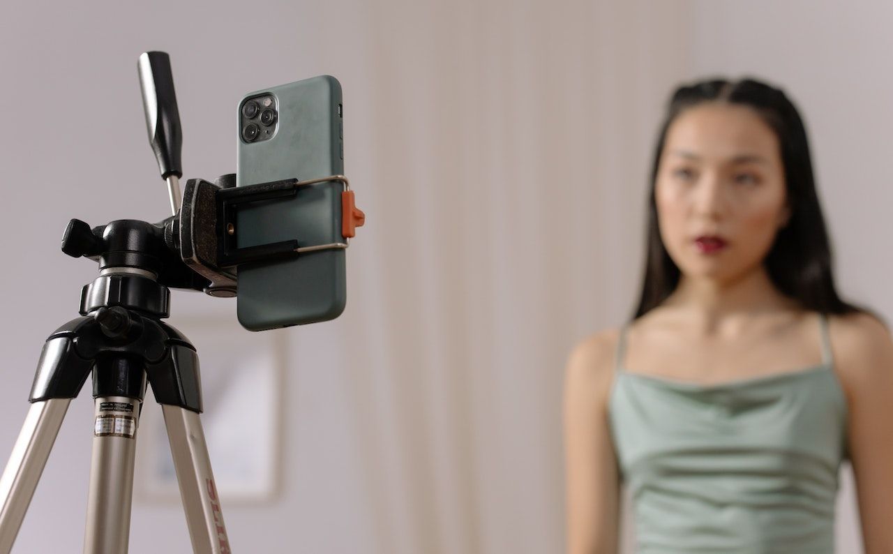 A woman starring at a smartphone mounted on a tripod