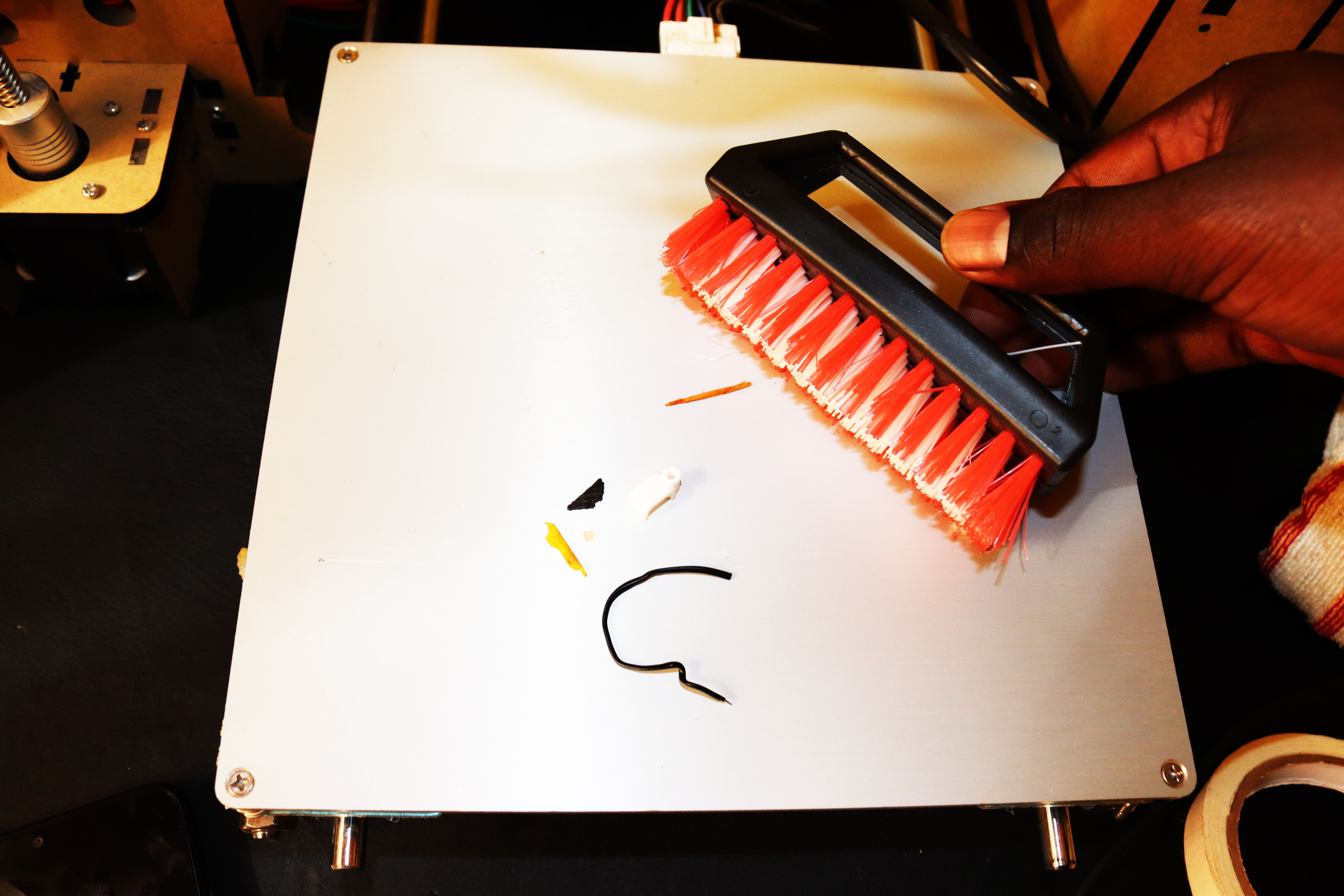 Using the brush to remove dirt and debri from the 3D printer bed