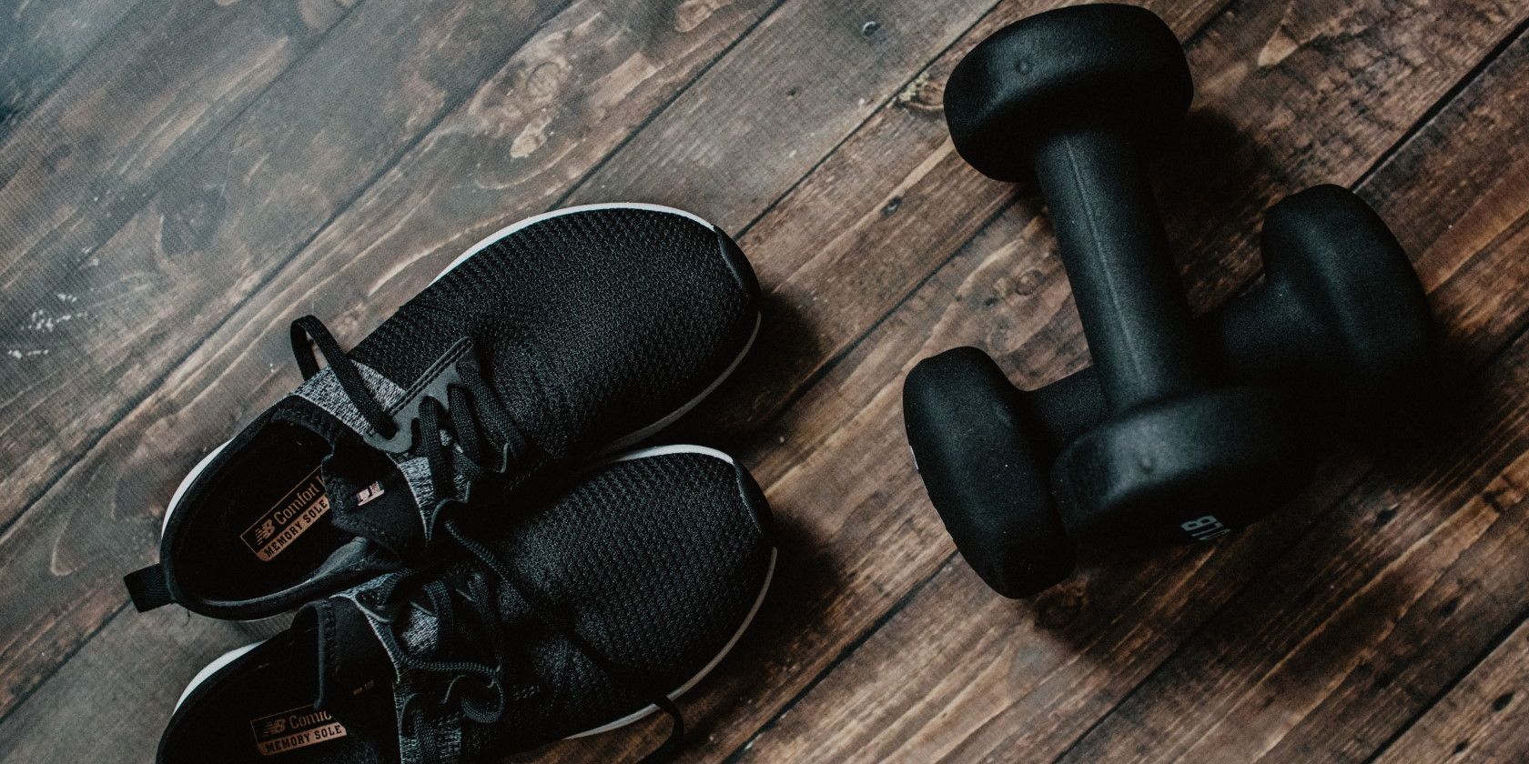 pair of black running shoes next to small black set of dumbbells