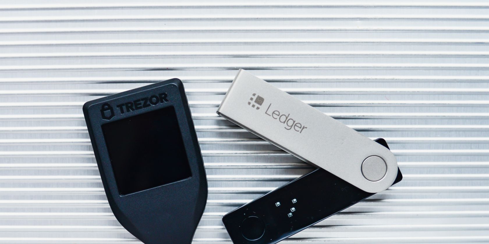 trezor and ledger hardware wallets on a white metal background
